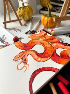 an orange and red snake is sitting on top of a white paper with markers in front of it