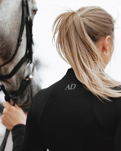 a woman is holding the bridle of a horse as it stands next to her