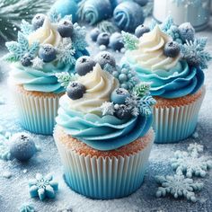 cupcakes decorated with frosting and blue decorations on a snow - covered table