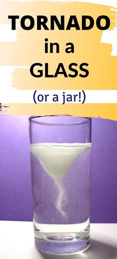 a glass filled with liquid sitting on top of a table next to a purple wall