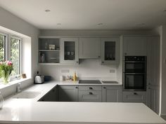 a kitchen with white countertops and gray cabinets next to a vase filled with tulips