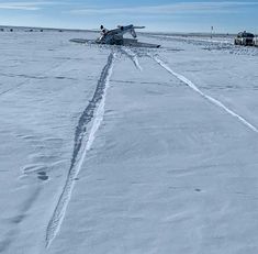 an airplane on the ground with tracks in the snow