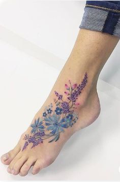 a woman's foot with blue and purple flowers on her left side, in front of white background