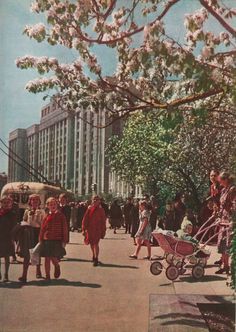 an old photo of people walking down the street with their baby in a stroller