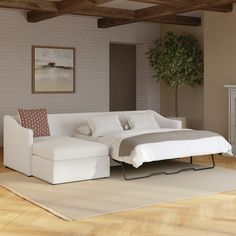 a living room with a white couch and a bed in the middle, on top of a hard wood floor