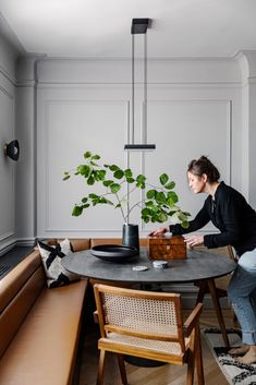 a woman sitting at a table in front of a potted plant on top of a wooden box