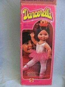 the doll is in its box and has a pink tutu skirt on it's head