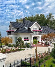 a large white house with pink flowers on the windows