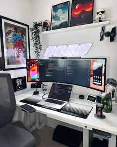 A developer's workspace featuring a large monitor flanked by smaller displays and a laptop on a white desk. The room is decorated with sci-fi and superhero art, including Star Wars helmets and Spider-Man posters, accentuated by triangular light panels above the monitor Ultrawide Setup, Dream Desk, Dream Video, Home Studio Setup, Star Wars Decor, Aesthetic Space, Setup Ideas, Gaming Room Setup, Computer Setup