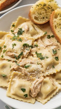 pasta with chicken and parmesan cheese on a plate next to two slices of bread