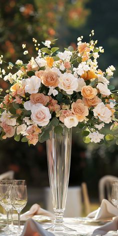 a vase filled with flowers sitting on top of a table next to two wine glasses