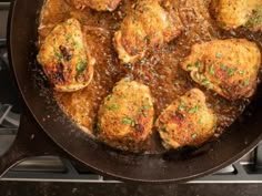 some meat patties are cooking in a skillet on top of the stovetop