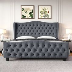 a gray bed with tufted headboard and foot board in a white walled room