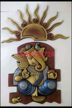 a decorative wall hanging with an elephant on it's face and sun above it