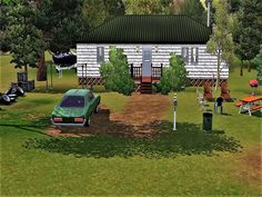 a green car is parked in front of a white house and picnic tables on the grass