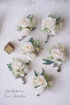 white flowers and greenery are arranged on a table