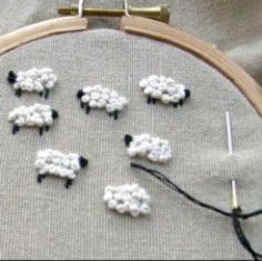 a close up of a cross stitch pattern with sheep on it and some thread in the middle