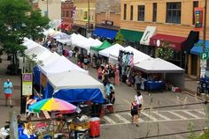 many tents are set up in the middle of a city street as people walk by