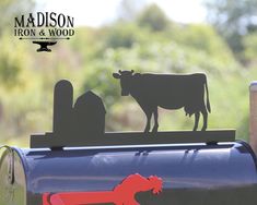 a cow standing on top of a mailbox with the word madison iron and wood