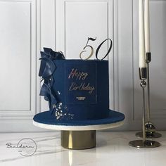 a blue birthday cake sitting on top of a table next to a lit candle and a white wall