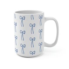 a white coffee mug with blue bows on the front and sides, sitting against a white background