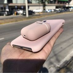 a hand holding a pink cell phone in front of a street