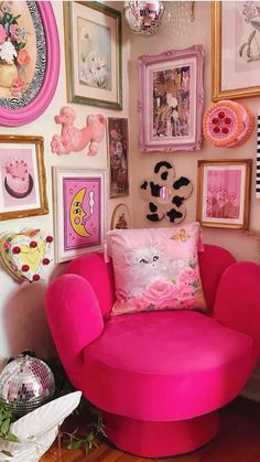 a pink chair sitting in front of a wall filled with pictures and other decor items