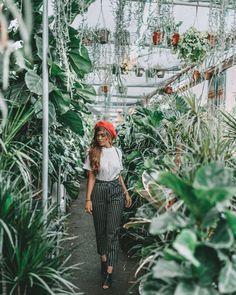 a woman standing in a greenhouse surrounded by plants