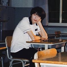 a young man sitting at a table in front of a laptop computer