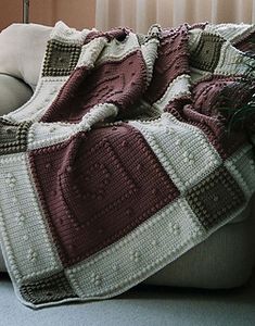 a couch with a blanket on it in front of a window and potted plant