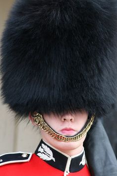 a close up of a person wearing a uniform with a big furry hat on his head