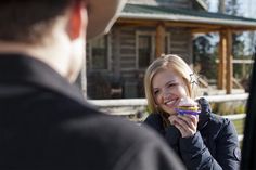 a woman holding a donut in front of a man who is looking at her