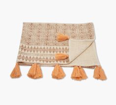 an orange and white blanket with tassels on it's edges, laying flat