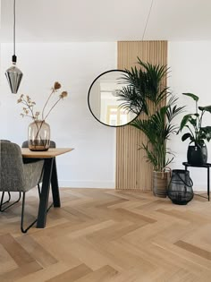 a living room with wooden floors and plants in vases on the table, mirror hanging from the wall