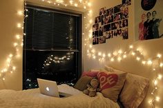 a laptop computer sitting on top of a bed in a room filled with pictures and lights