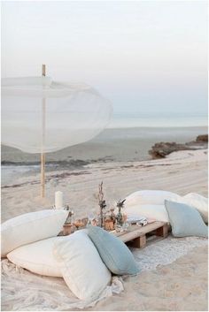 there is an umbrella and pillows on the beach