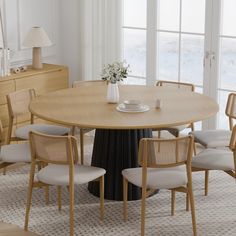 a dining table with chairs around it and a vase on the table next to it