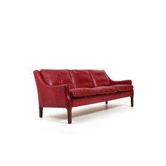 a red leather couch sitting on top of a white floor next to a wooden frame