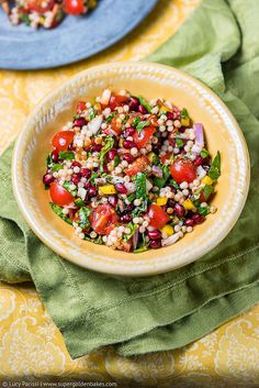 a salad in a bowl on top of a yellow table cloth next to a blue plate