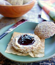 two cookies on a plate with jam in the middle and a bowl behind them, ready to be eaten