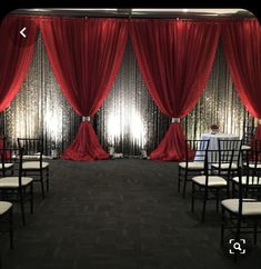 the room is decorated with red drapes and white chairs