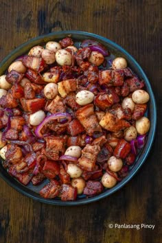 a bowl filled with meat and onions on top of a wooden table