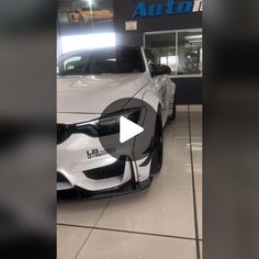 a white car parked in front of a auto showroom with an advertisement on it