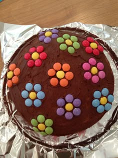 a chocolate cake decorated with colorful candies on aluminum foil