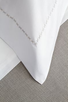 a close up of a bed with white sheets and pillow cases on top of it