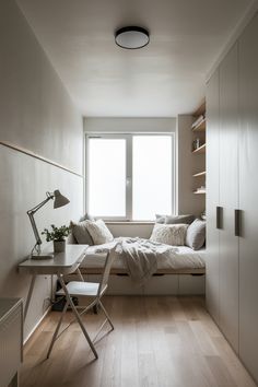 a bedroom with a bed, desk and chair next to a window in the corner