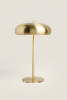 a gold table lamp sitting on top of a white surface