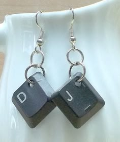 a pair of black and white dice earrings with the letters d and j on them