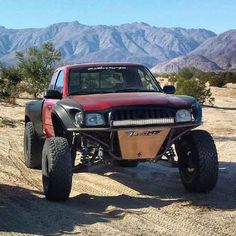 a red truck parked on top of a dirt road