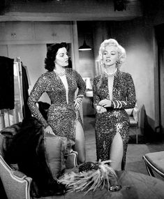 two women dressed in animal print outfits standing next to each other on couches and chairs